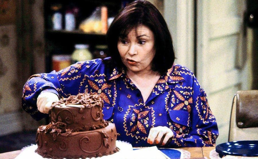 Roseanne cutting a cake 