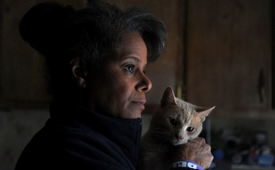 Debi Thomas holding her cat and looking away from the camera 