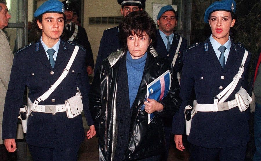 Patrizia Reggiani being escorted to court by police officers. 