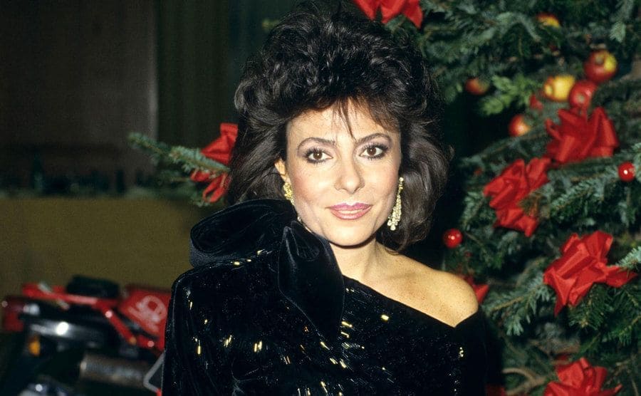 Patrizia Reggiani dressed in an elegant black gown during a Christmas party. 