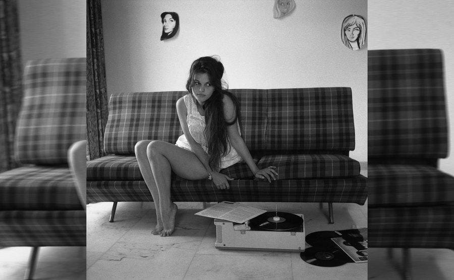 Claudia Cardinale sitting on a plaid sofa listening to a vinyl 