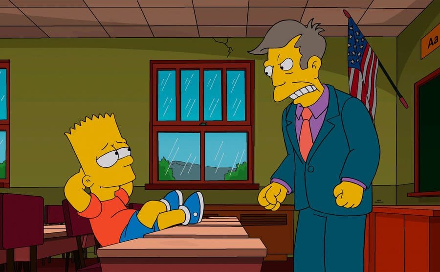 Bart Simpson with his feet up on a school desk with Principal Skinner looking at him angrily.