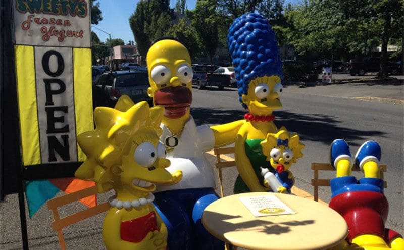 The Simpsons figures sitting outside of a Frozen Yogurt shop. 
