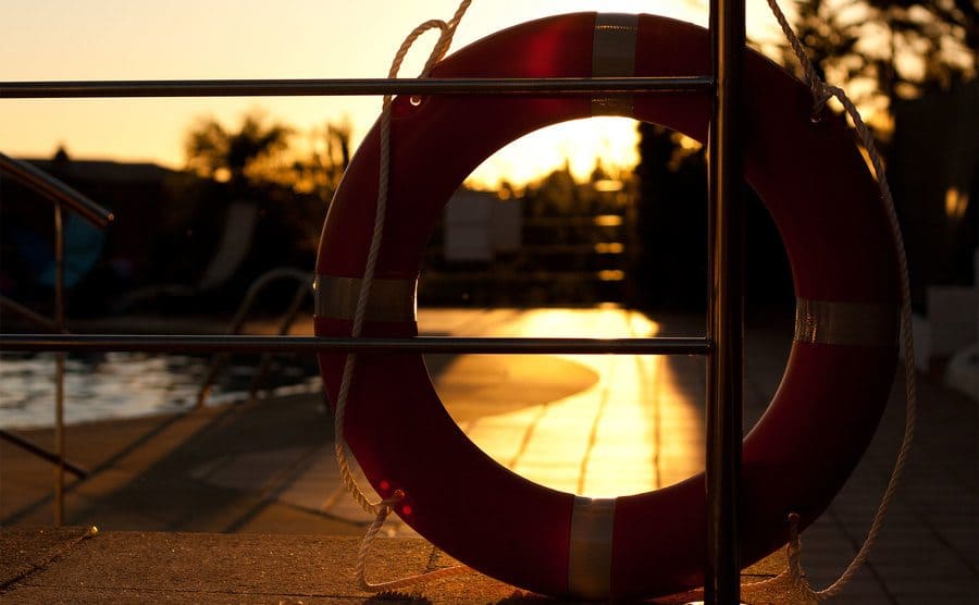 Lifeguard float silhouette illuminated by the golden light of the sun at sunset next to a pool