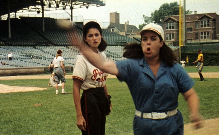 Rosie O’Donnell and Madonna are practicing throwing balls on a field. 