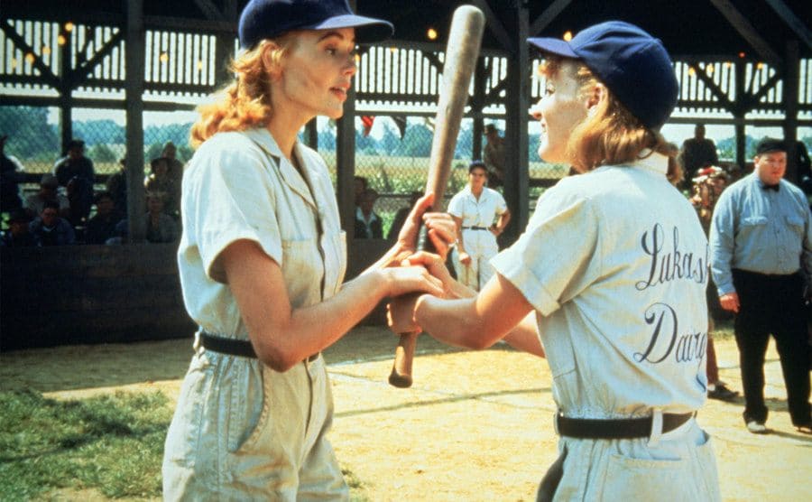 Geena Davis and Lori Petty are fighting over a baseball bat. 