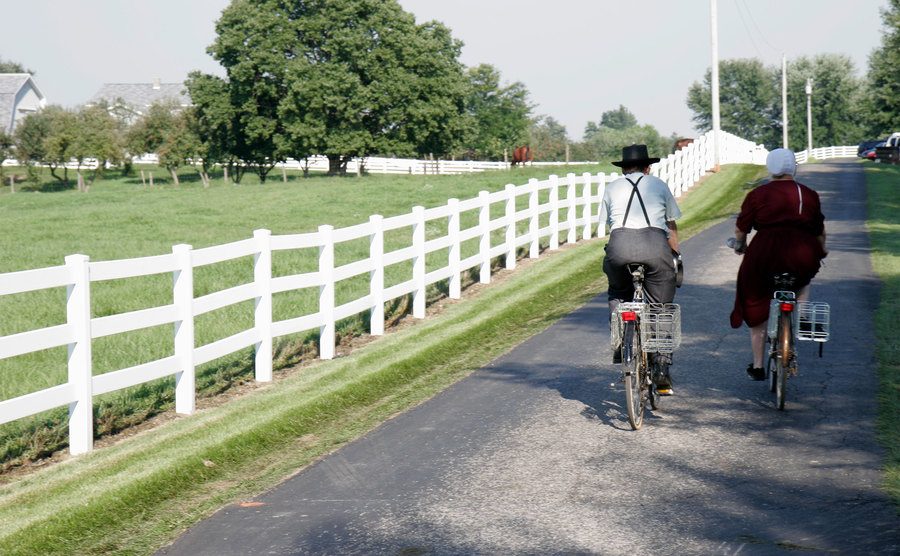 An Amish couple riding bicycles on a country lane.