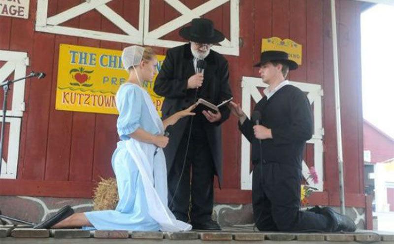 An Amish couple are on their knees before their bishop during a wedding ceremony. 