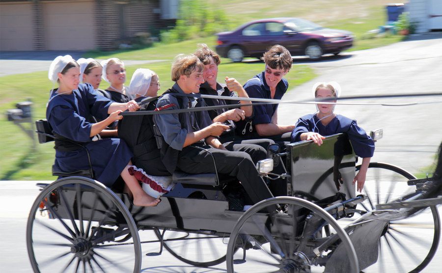 Amish teens race in their horse-drawn carriage down the street. 