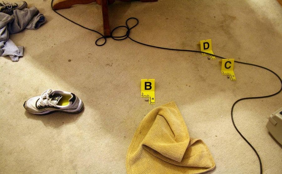 Police marked evidence found at the crime scene like a shoe, towel, and cable on the carpet floor.