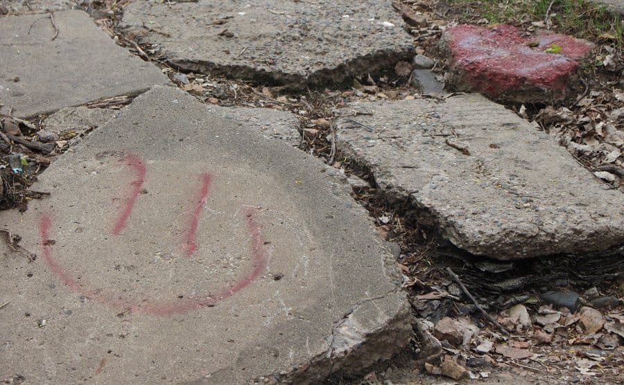 A smiley face graffitied on to some rubble. 