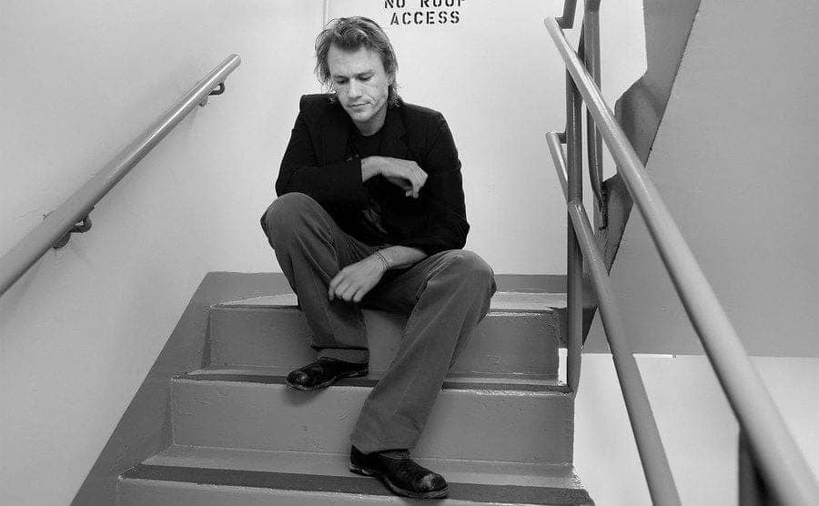 Ledger is sitting alone in a stairwell. 