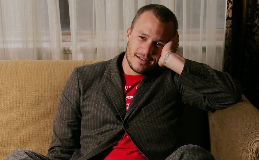 Heath Ledger poses for a portrait while sitting on a couch. 