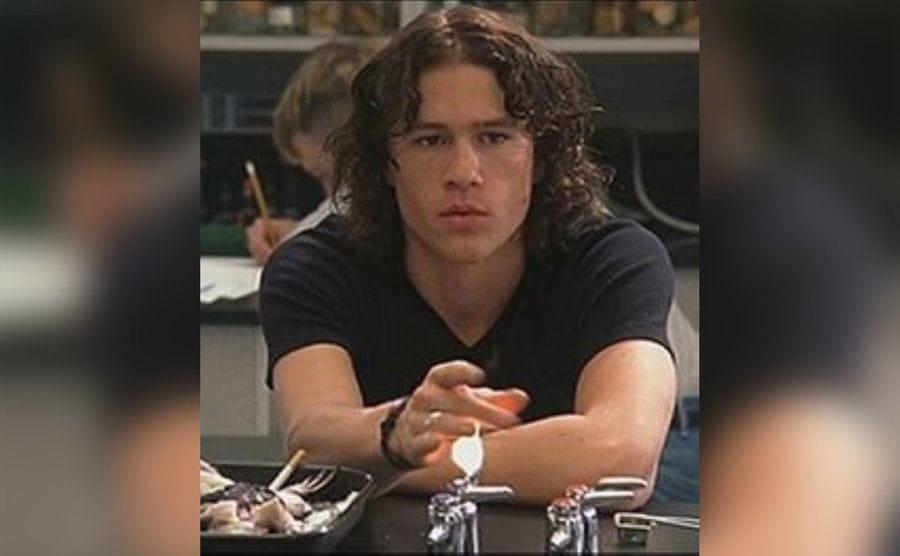 Heath Ledger is playing with fire coming out of a Bunsen burner in a scene from ’10 Things I Hate About You’.