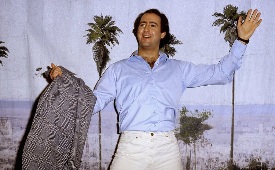 Andy Kaufman is posing in front of a tropical backdrop. 