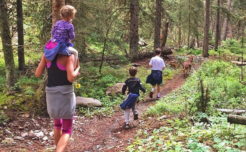 Gisele and the kids are hiking in the forest.