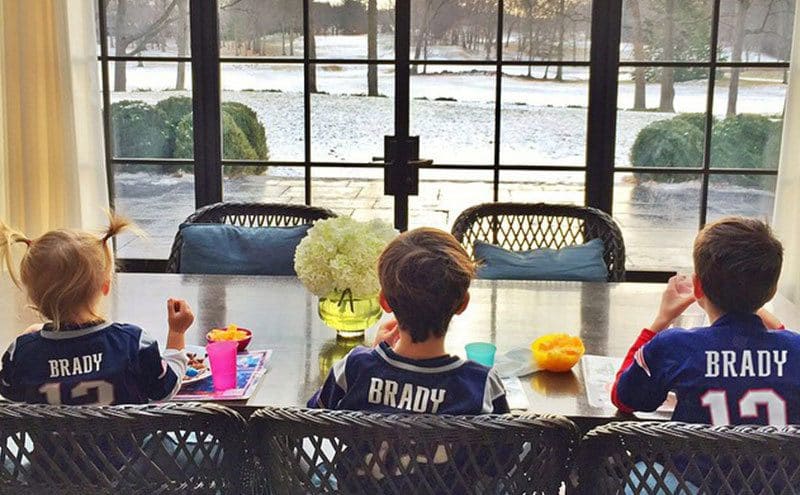 The three kids of the family are having breakfast dressed in Tom Brady's 12 soccer shirts.
