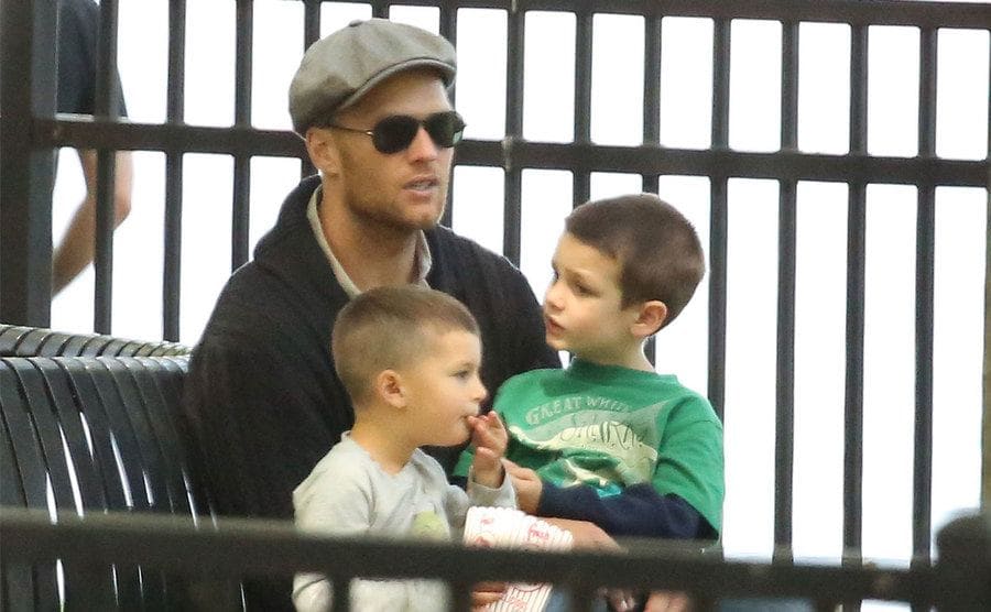 Tom Brady is sitting on a park bench with his two sons, circa 2013.