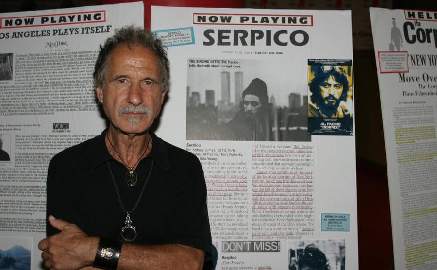 Frank Serpico, former New York City Police Officer, poses in front of three movie posters SERPICO starring Al Pacino.