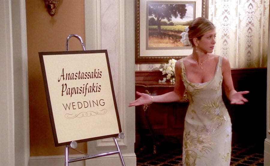 Jenifer Aniston stands by a sign that says “Anastassakis Papasifakis Wedding”. 