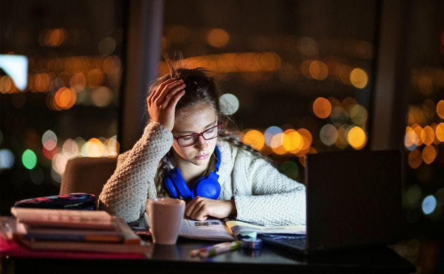 Teenage girl looking stressed as she studies late at night. 