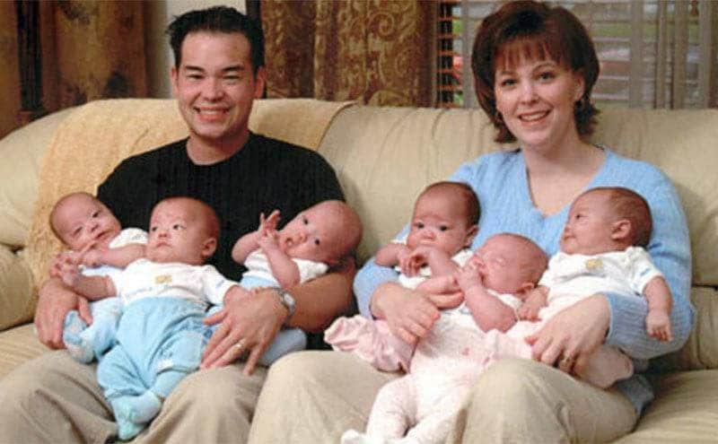 Kate and Jon sit on the couch as they hold their sextuplets. 