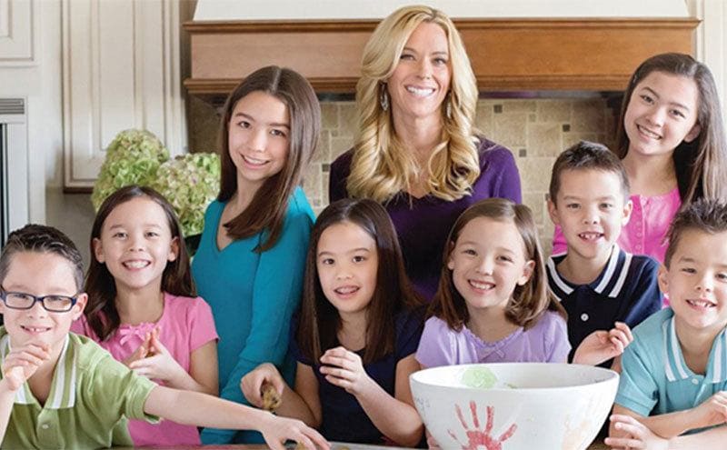 Kate and her eight children are in the kitchen making cookies. 