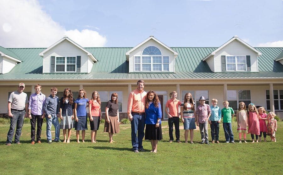 Jim and Michelle Duggar stand with all of their children behind them. 