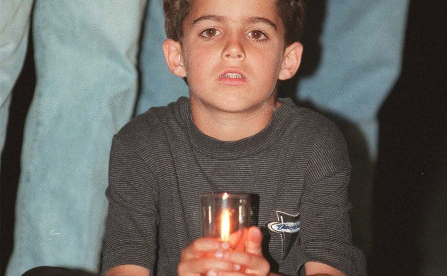 Justin Simpson sits holding a candlelight vigil for his mother.