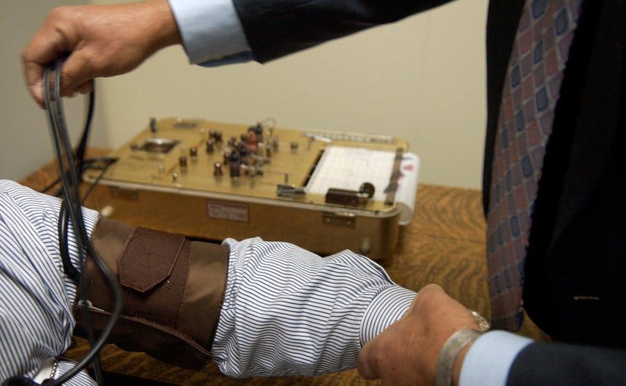 A man is being hooked up to a polygraph machine. 