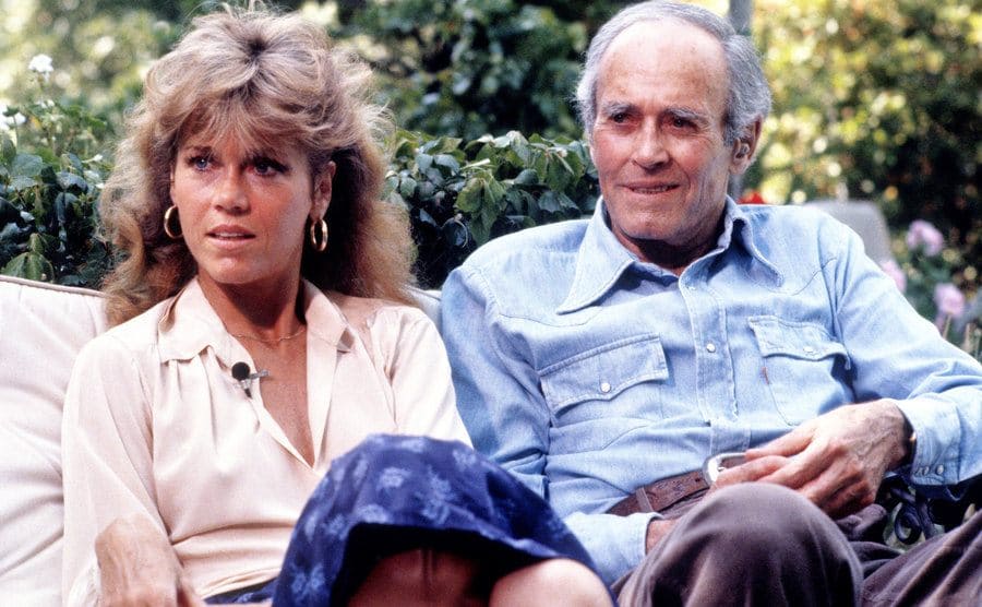 Jane Fonda and Henry Fonda are sitting outdoors. 