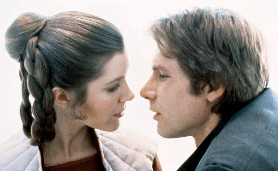Carrie Fisher and Harrison Ford are about to kiss during the filming of Star Wars.