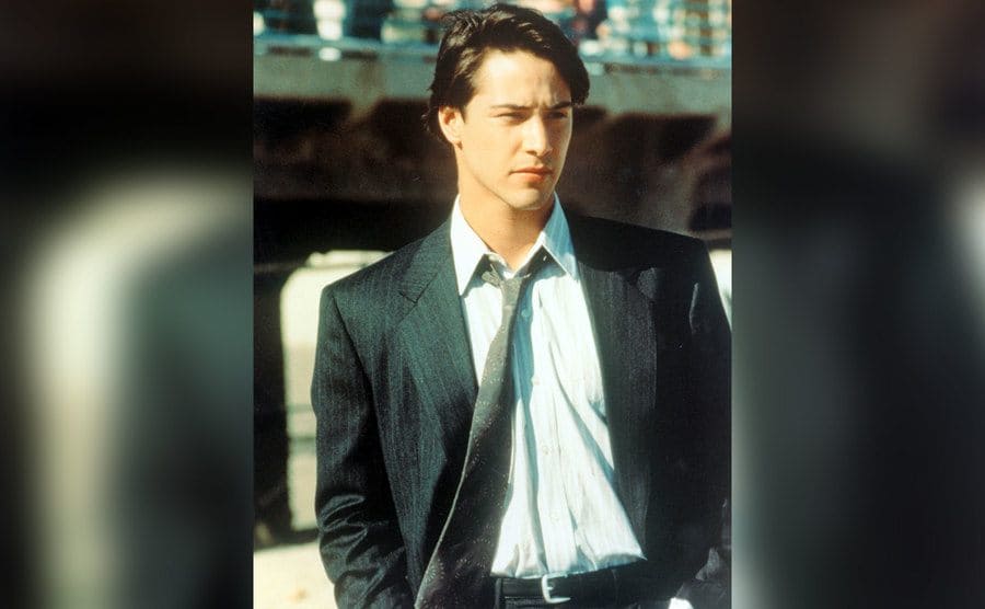 Reeves poses in a suit and tie as FBI agent Johnny Utah. 