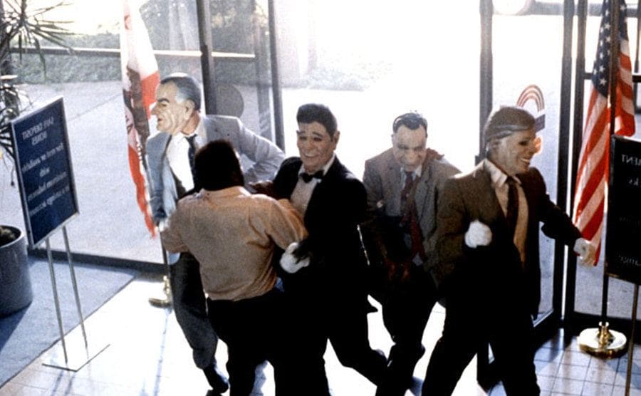 The “Ex-Presidents” push past the bank security guard as they rob the bank. 