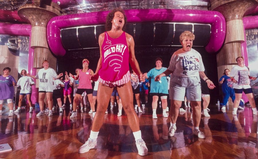 Richard Simmons is coaching a class full of people. 