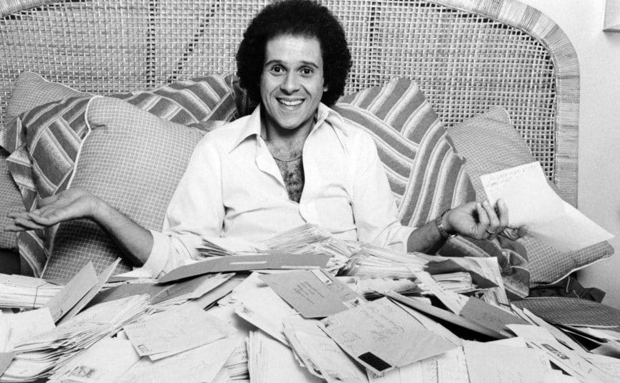 Richard Simmons poses in bed covered by fan mail.