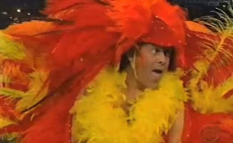 Richard Simmons is wearing a turkey costume made from big feathers. 