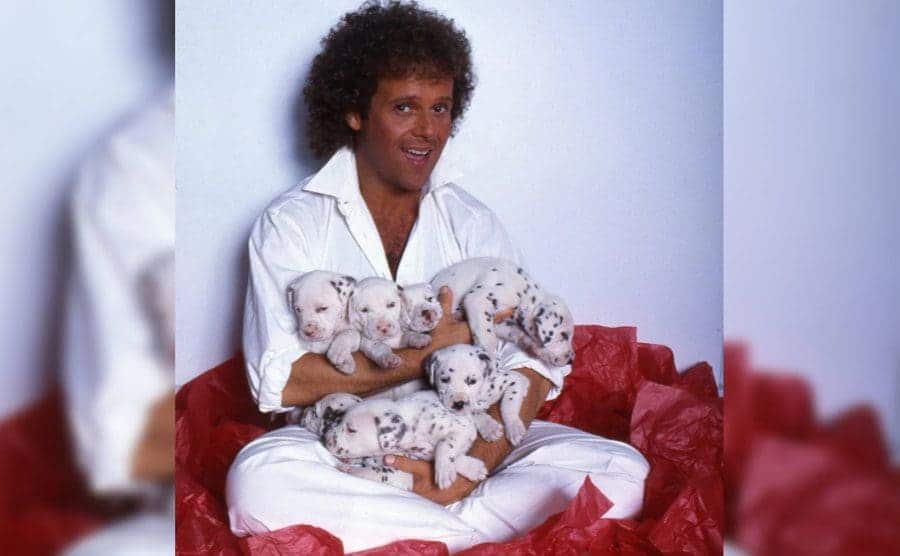Richard Simmons poses holding his dalmatian puppies 