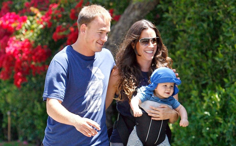 Alanis Morissette, Mario Treadway, and their baby boy Ever Imre are walking outside. 