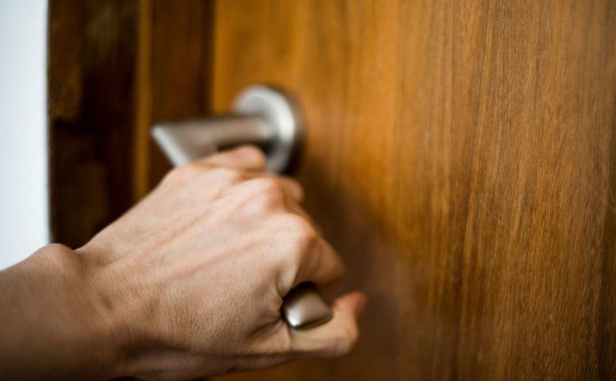 A hand trying to open a door handle. 