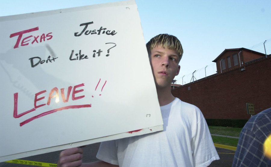 A boy holds poster that reads ‘’Texas Justice.’’