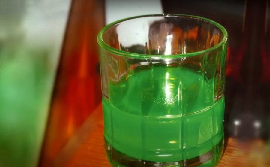 A glass filled with a neon green liquid. 