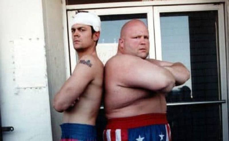 Johnny Knoxville and Butterbean standing back to back. 