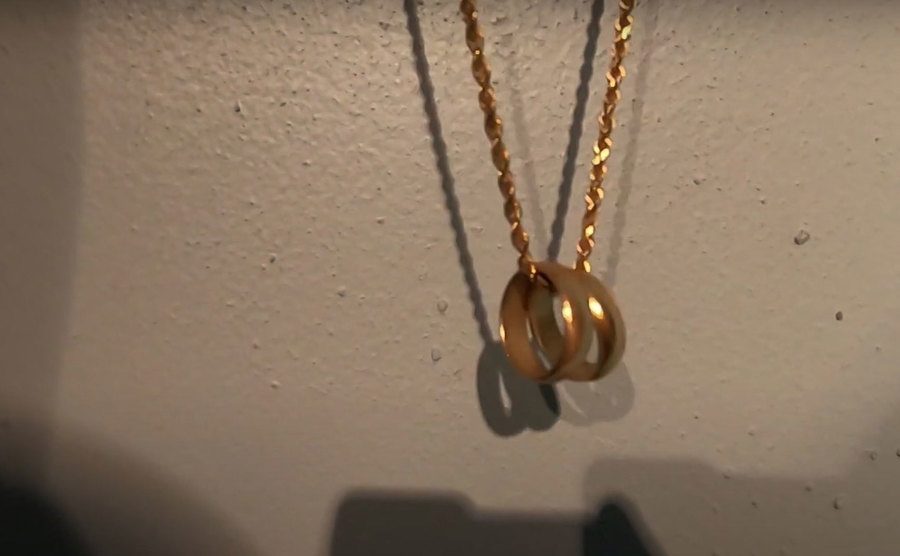 Two wedding rings are attached to a necklace. 
