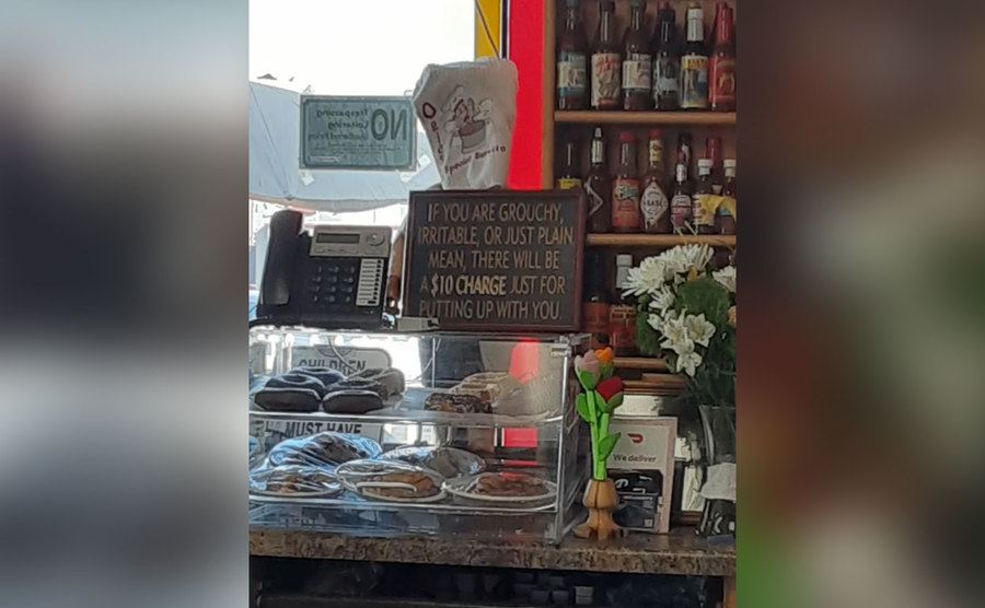 A sign in a cafe that says all mean costumers will receive an additional 10 dollar charge. 