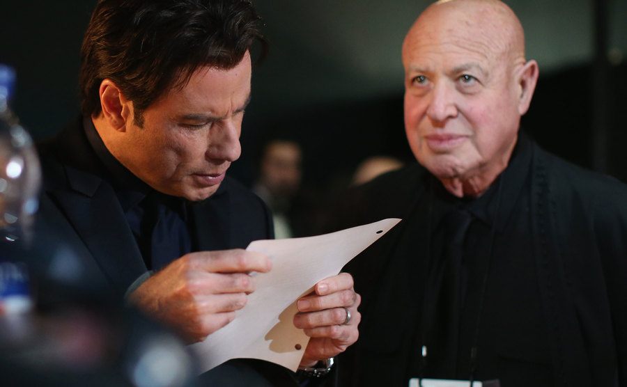 John Travolta reads backstage during the Oscars.