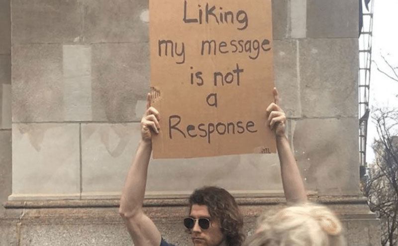 A man is holding a sign that reads ‘’Liking my Message is Not a Response.’’