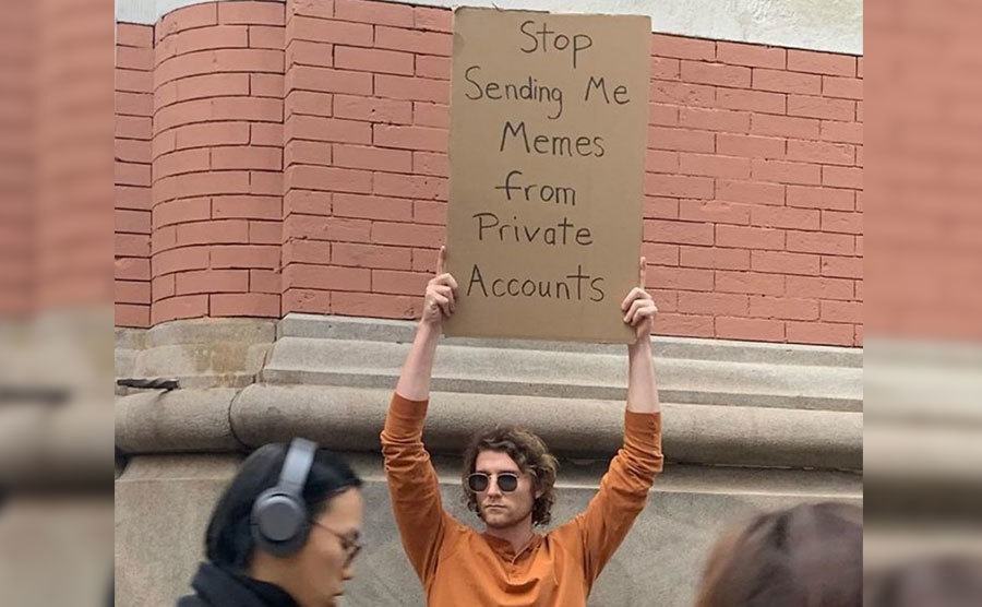 A man is holding a sign that reads ‘’Stop Sending me Memes from Private Accounts.’’