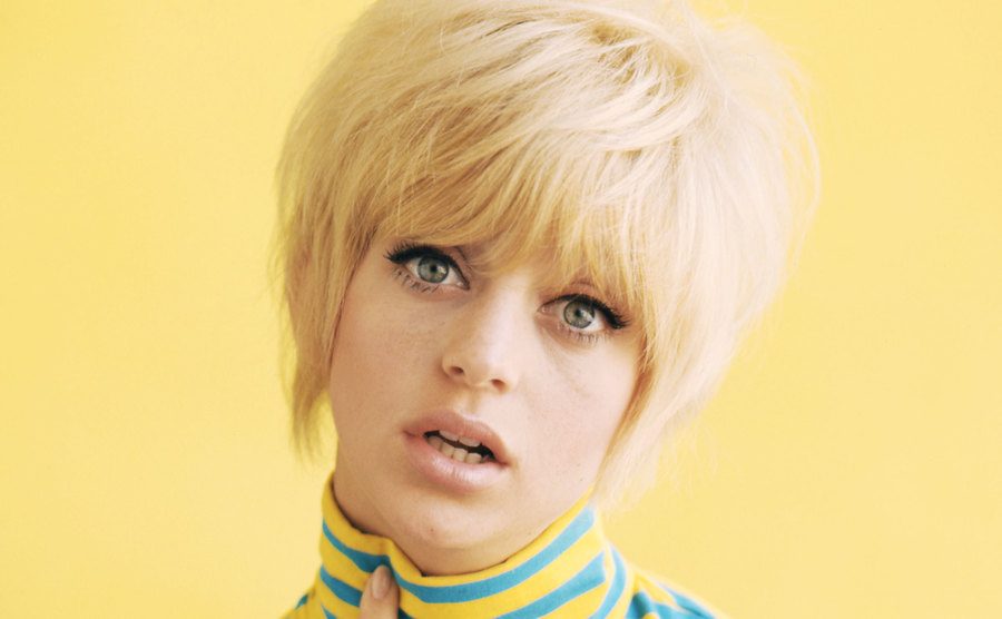 Goldie Hawn poses against a yellow background. 
