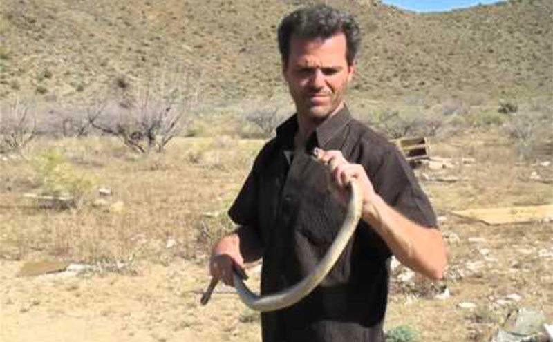 Kenny holds up a rattlesnake in his bare hands. 